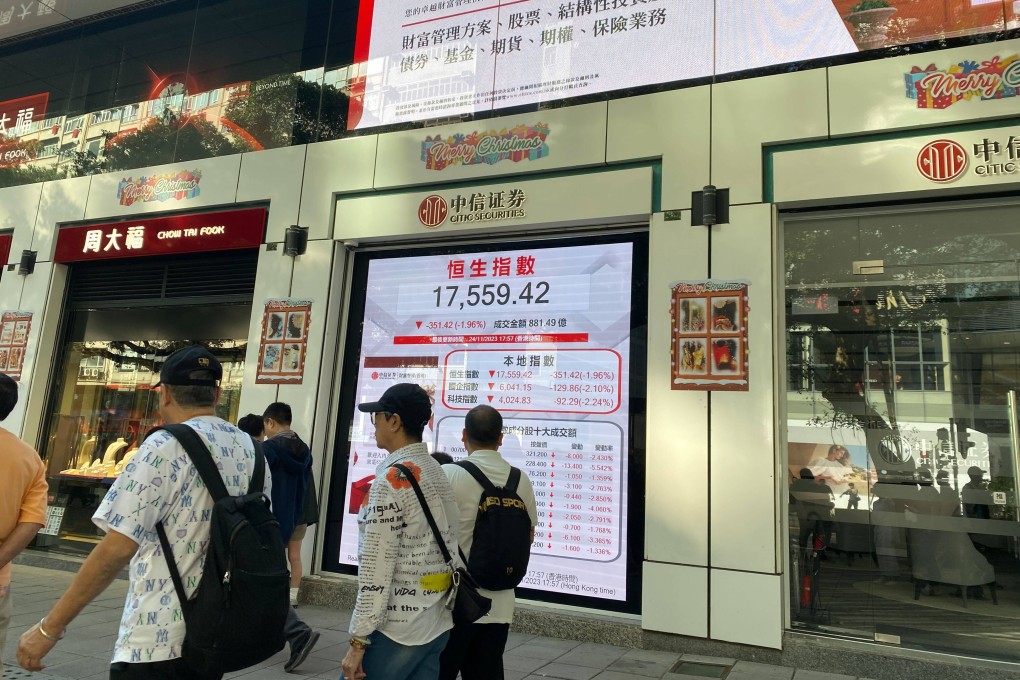 People walking past a screen showing the Hang Seng Index outside a bank branch in Tsim Tsa Tsui, Hong Kong on November 26. Phoyto: Li Jiaxing