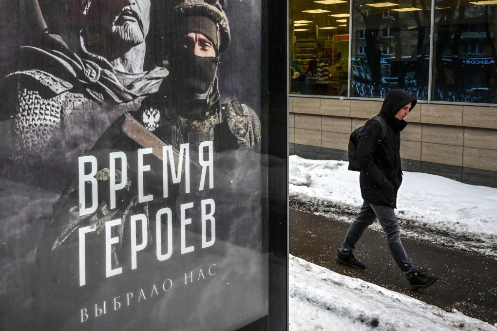A pedestrian walks past a social advertisement billboard showing a Russian soldier in front of his ancient predecessor and reading “The Time of Heroes Has Chosen Us” displayed on a street in Moscow. Photo: AFP