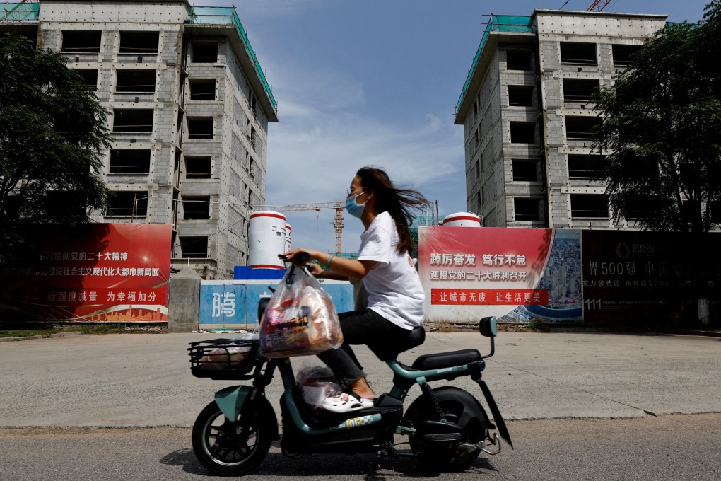 A woman rides a scooter past a construction site for residential buildings by indebted Chinese developer Country Garden in Tianjin on August 18. Photo: Reuters