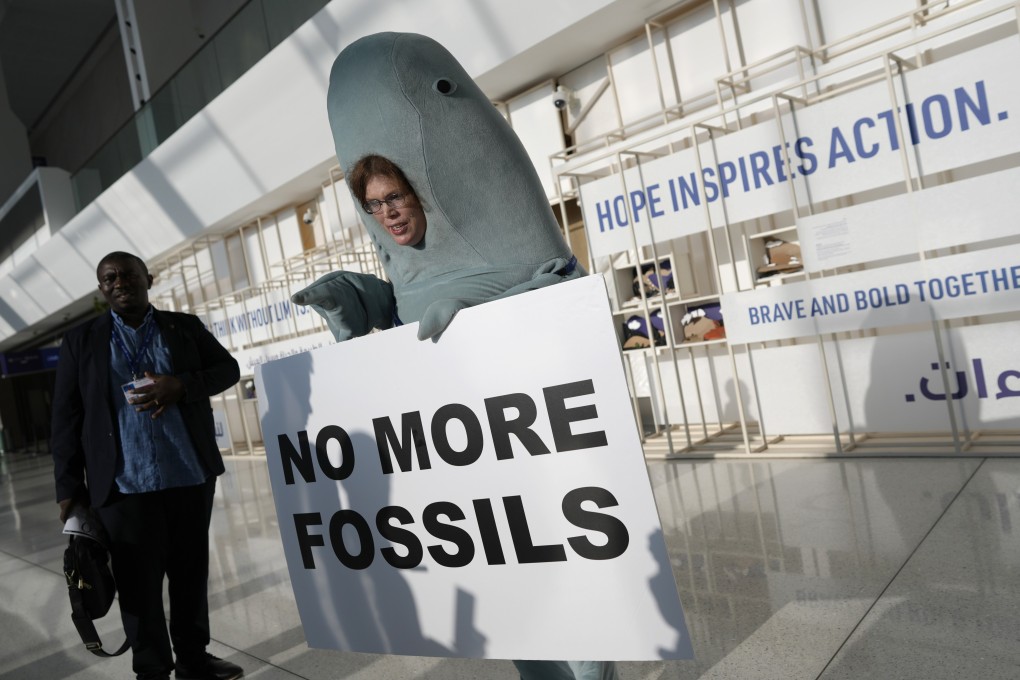 Environmentalist Alice McGown holds a sign reading “no more fossils” while dressed as a dugong at the COP28 UN Climate Summit in Dubai on Sunday. Photo: AP