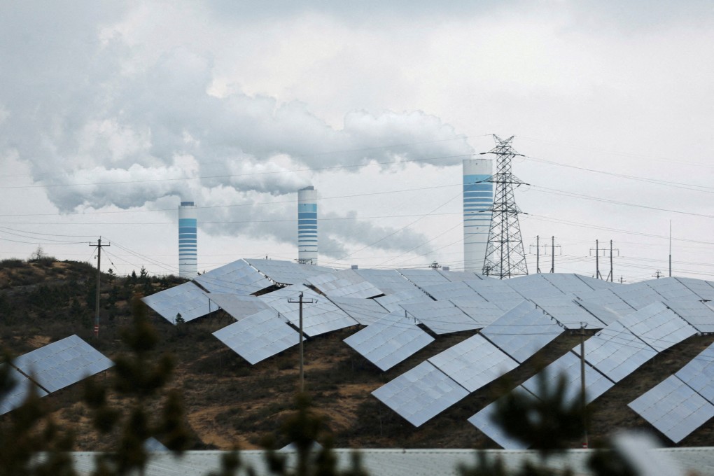 Industrial chimneys loom behind solar panels in Shaanxi province, China on April 24, 2023. Photo: Reuters