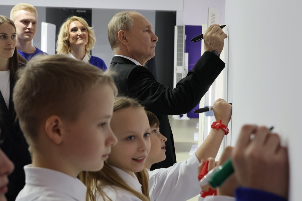 Russian President Vladimir Putin writes on a wall during a visit to the Russia Expo international exhibition in Moscow. Photo: EPA-EFE