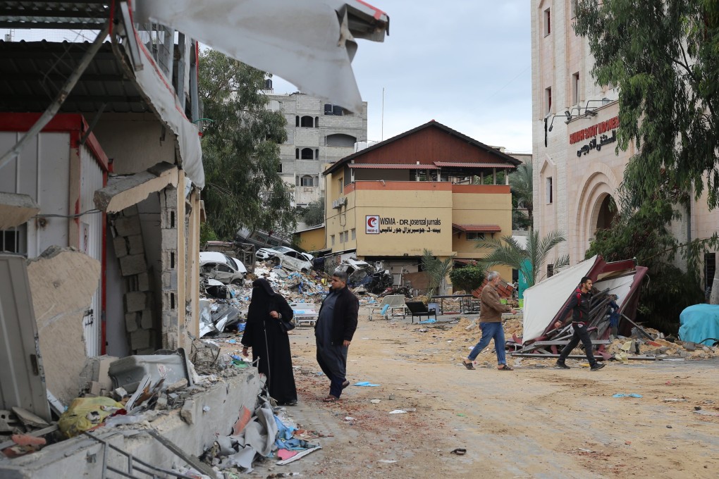 People walk amid rubble near the destroyed Indonesian hospital in Beit Lahia, north of the Gaza Strip, in Palestine on November 29. Healthcare facilities and workers have come under attack in recent conflicts despite international laws meant to ensure their safety. Photo: dpa