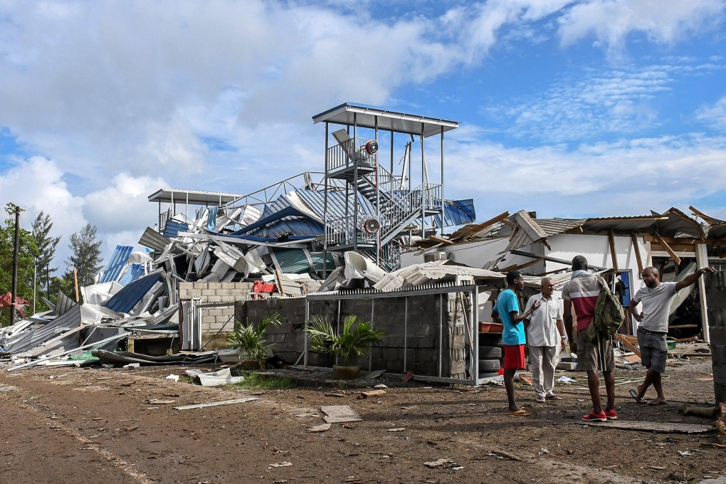 People gather next to damaged buildings following an explosion at the Providence industrial area in Mahe, Seychelles on Thursday. Photo: AFP