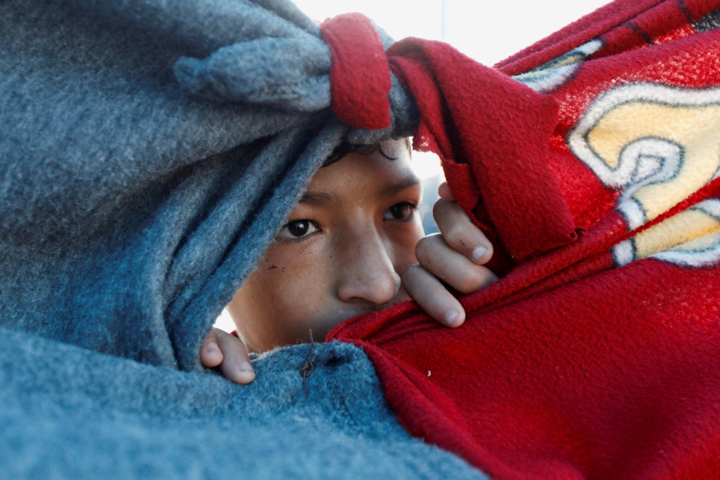 A displaced Palestinian boy, who fled his family house due to Israeli strikes, looks through the cover of a tent at a camp sheltering displaced people in Rafah on Friday. Photo: Reuters