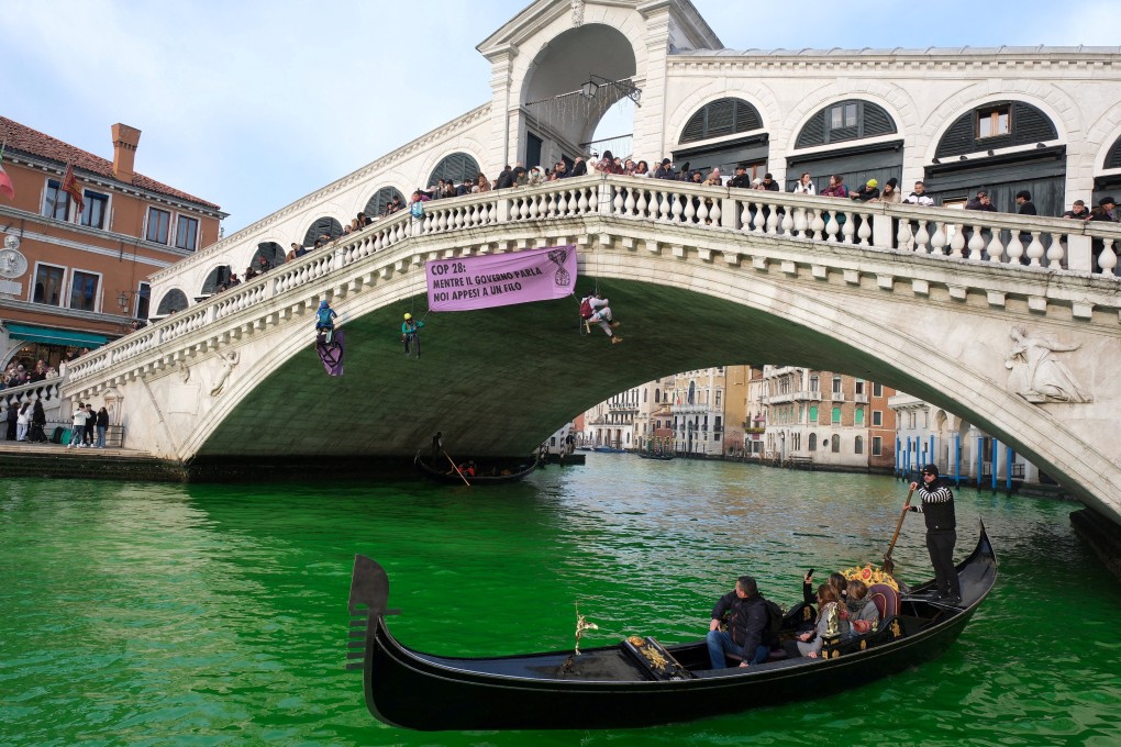People ride in boats as climate activists turn the waters of Venice’s Grand Canal green on Saturday. Photo: Reuters