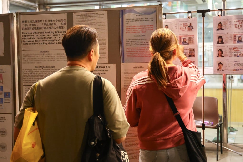 Voters check candidate information outside a polling booth in Wong Tai Sin. The electoral watchdog says the electronic voter registration system started experiencing problems at 7.42pm, which prevented ballot papers from being issued. Photo: Dickson Lee