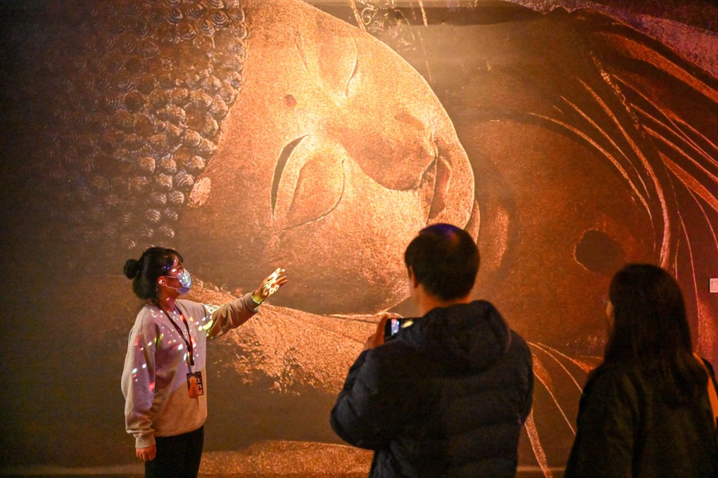 A guide introduces a work at an exhibition on Dunhuang culture at the Tianjin Digital Art Museum in Tianjin on November 28. In recent years, China has seen significant climate-related damage to its cultural heritage sites, including the Dunhuang caves. Photo: Xinhua