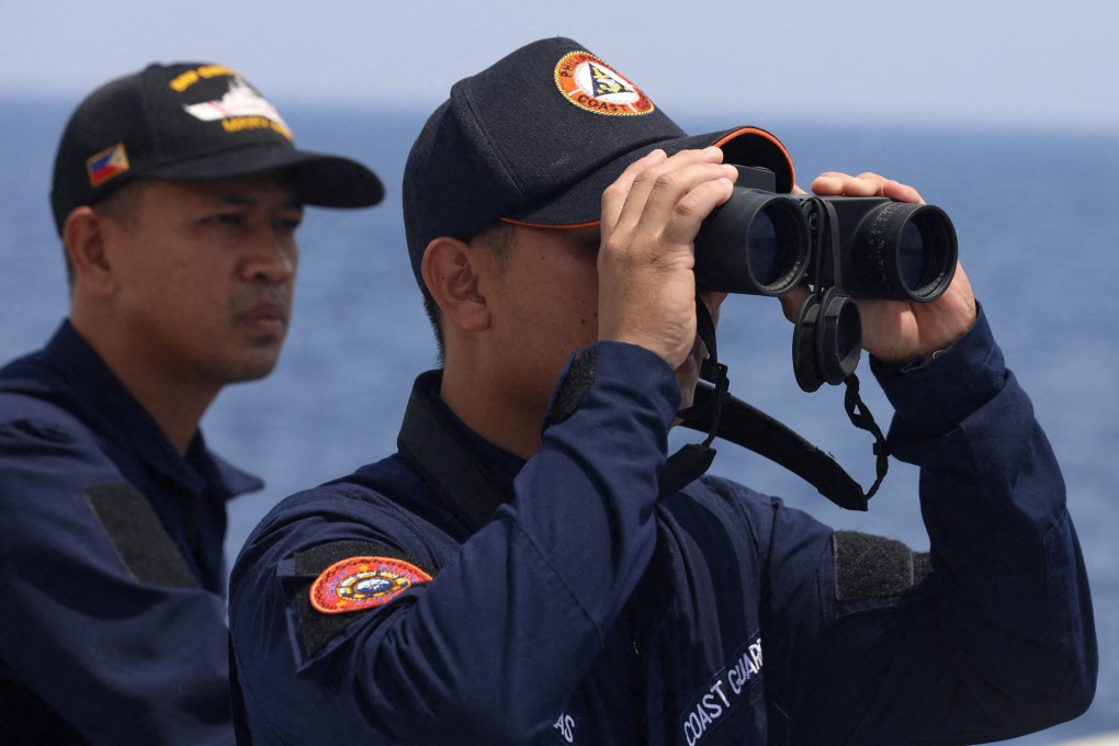 FILE PHOTO: A Philippine Coast Guard personnel looks through a binocular while conducting a resupply mission for Filipino troops stationed at a grounded warship in the South China Sea. Photo: Reuters