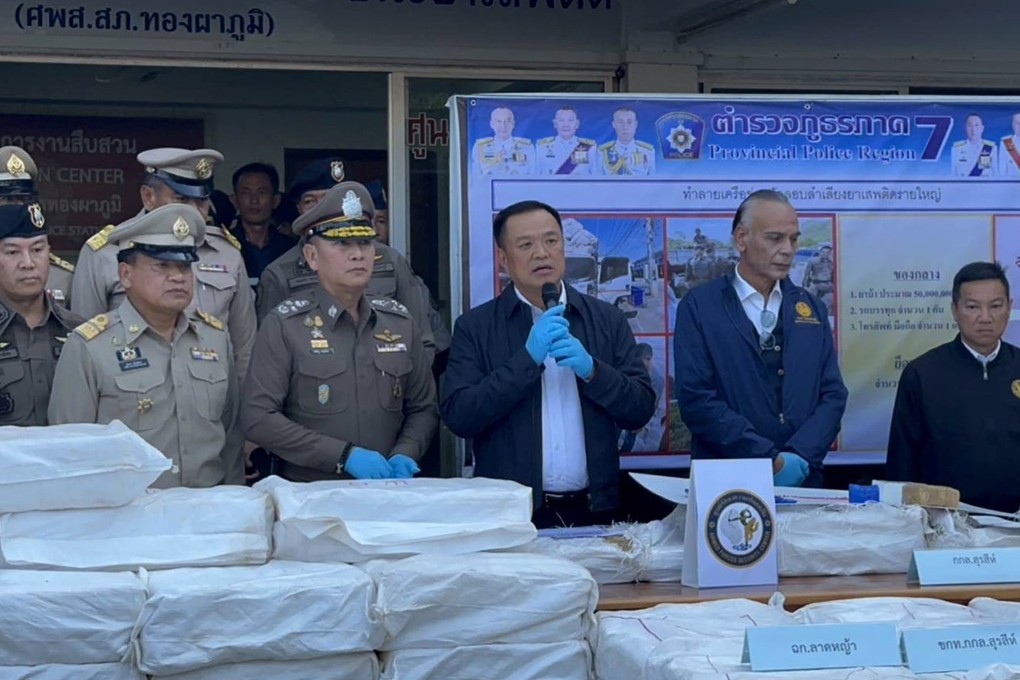 Thai Deputy Prime Minister Anutin Charnvirakul holding a microphone and standing behind a pile of 50 million confiscated methamphetamine pills on Tuesday. Photo: EPA-EFE