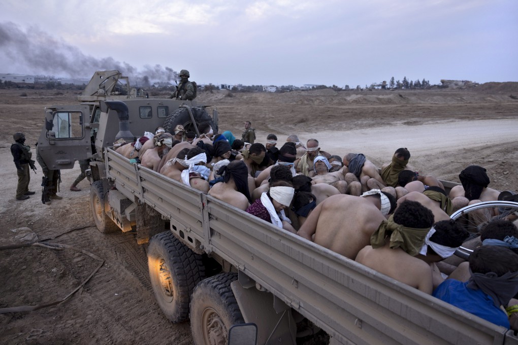 Israeli soldiers stand by a truck packed with bound and blindfolded Palestinian detainees in Gaza. Photo: AP