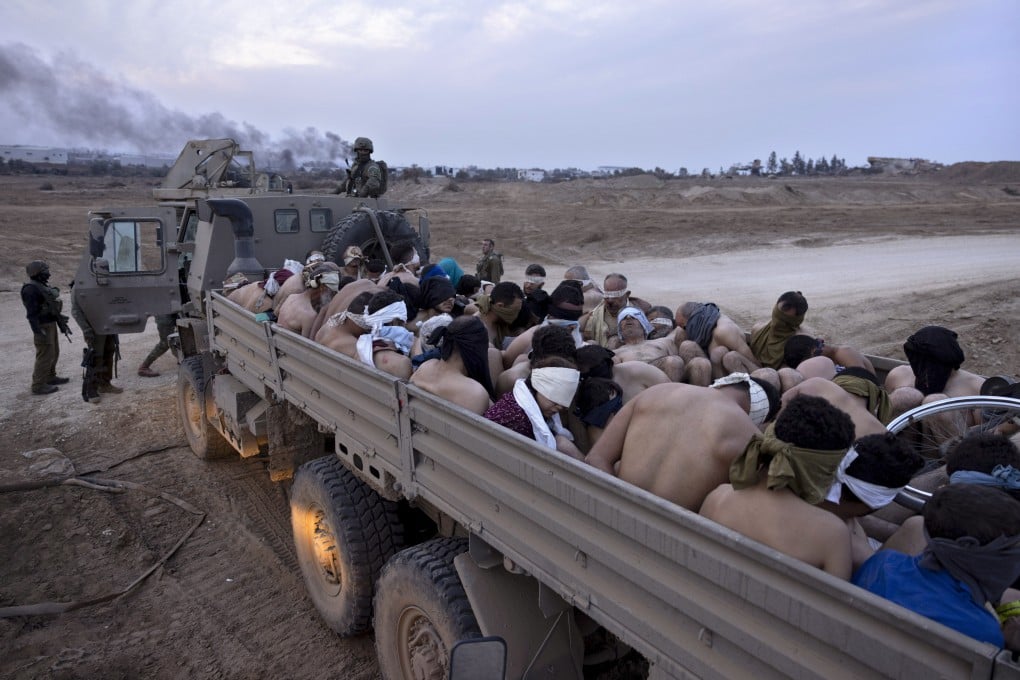 Israeli soldiers stand by a truck packed with bound and blindfolded Palestinian detainees in Gaza. Photo: AP