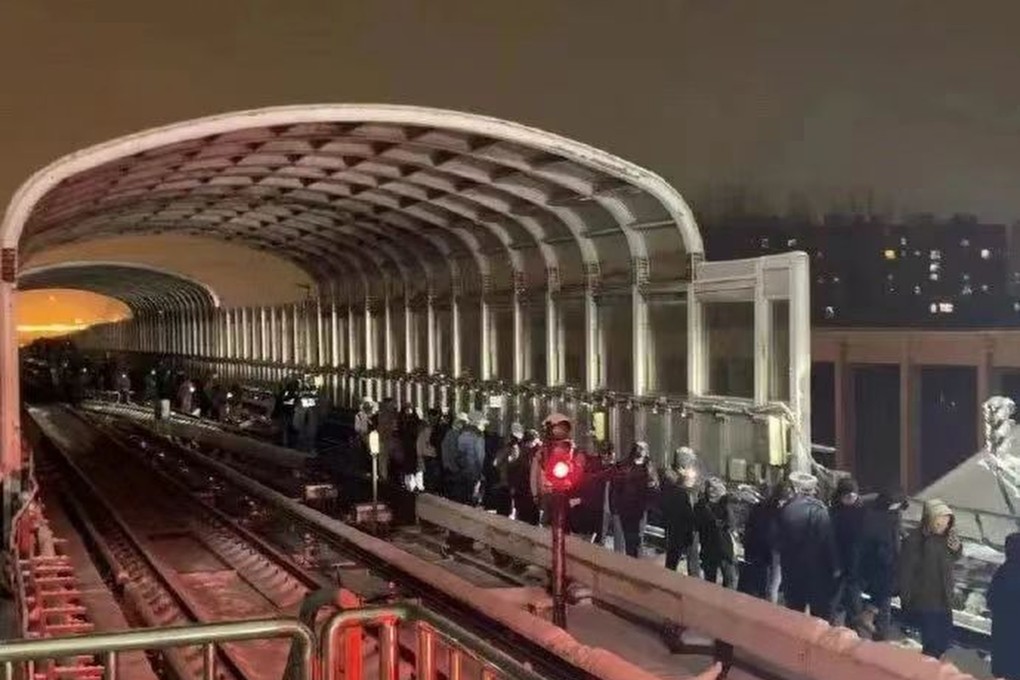 Passengers leave the stricken carriages with the help of Beijing Subway staff after an incident on the Changping line injured more than 100 people during severe snowstorms in northern China. Photo: Weibo