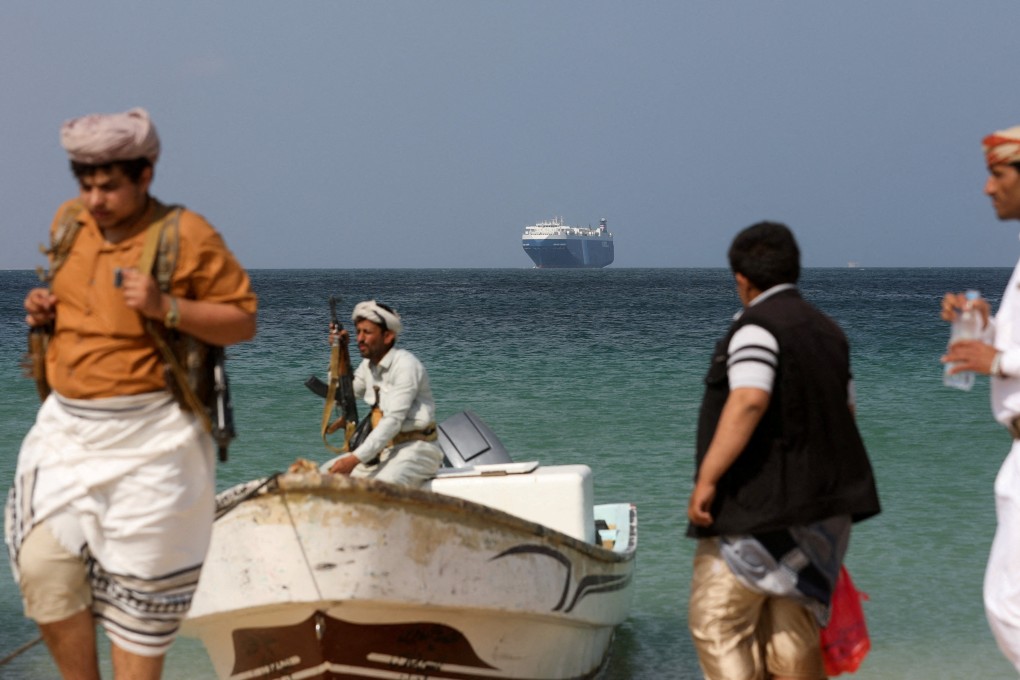 Armed men stand on the beach as the Galaxy Leader commercial ship, seized by Yemen’s Houthis last month, is anchored off the coast of al-Salif, Yemen. Photo: Reuters
