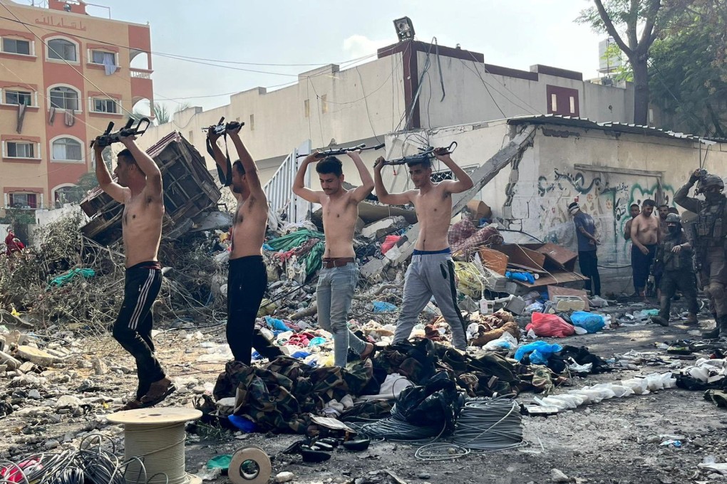 Men holding raised weapons are led out by Israeli soldiers near Kamal Adwan hospital in a photo released on Thursday. Photo: Israel Defence Forces via Reuters