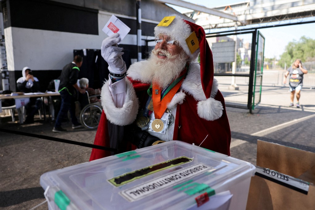 A citizen dressed as Santa Claus in Santiago, Chile, holds a ballot during the referendum on the new constitution. Photo: Reuters