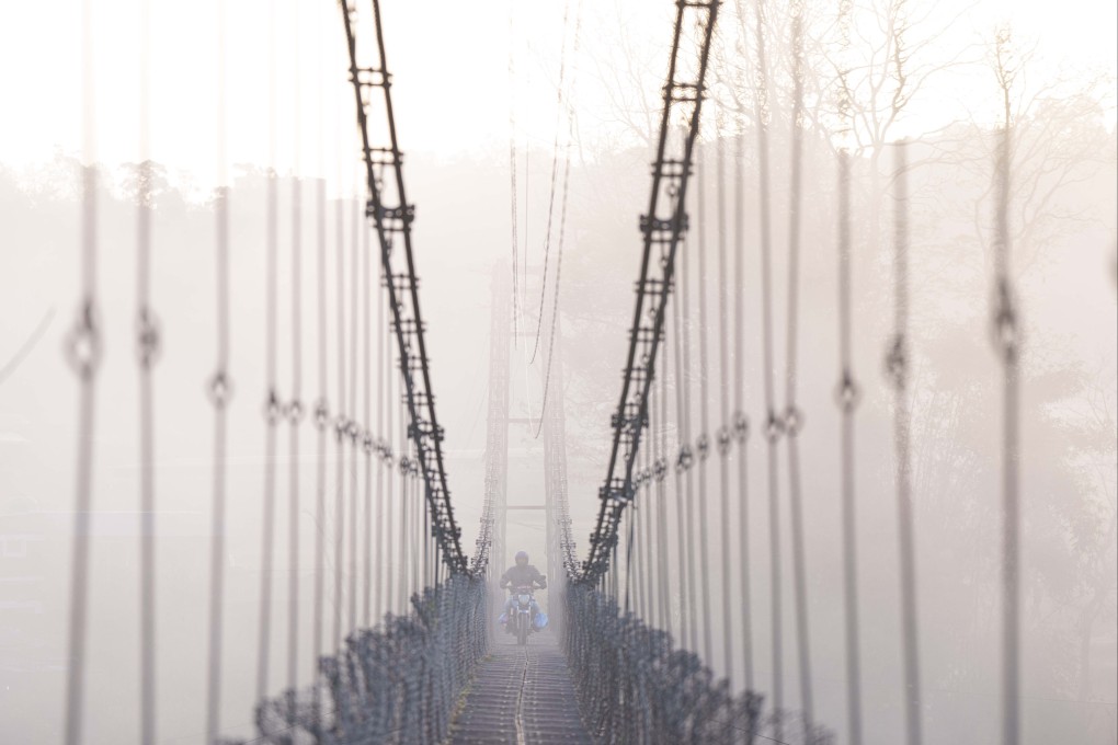 A man on a motorcycle crosses a suspension bridge over the Bagmati river in Lalitpur, Nepal, on March 27. Nepal has significant potential for generating surplus energy from hydropower  Photo: AP