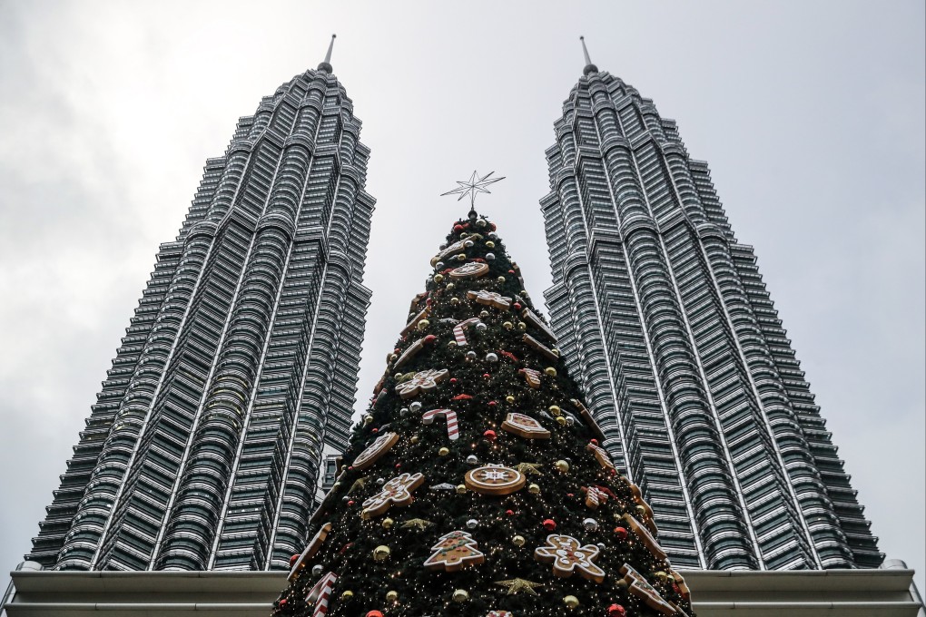The tallest Christmas tree replica in Malaysia standing at 32 meters, between the Petronas Twin Towers in Kuala Lumpur. A bakery chain banning staff from placing Christmas greetings on their cakes for fear of losing their halal status has brought into stark focus the threat of rising conservatism in Malaysia. Photo: EPA-EFE