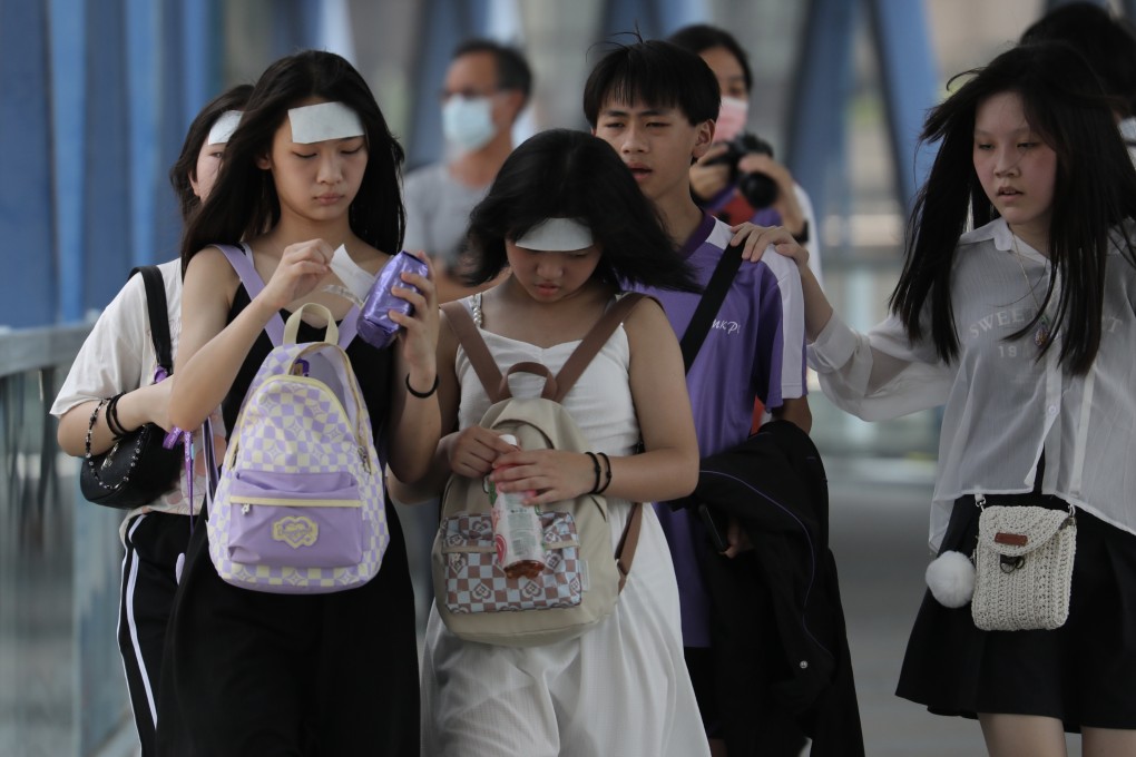 Pedestrians walk down a footbridge, in Central, Hong Kong, with cooling pads on their foreheads during a hot day in June. Photo: Xiaomei Chen