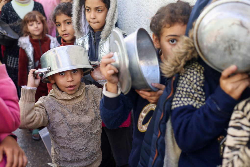 Palestinian children carry pots as they queue to receive food cooked by a charity kitchen in Rafah in the southern Gaza Strip on December 14. Photo: Reuters