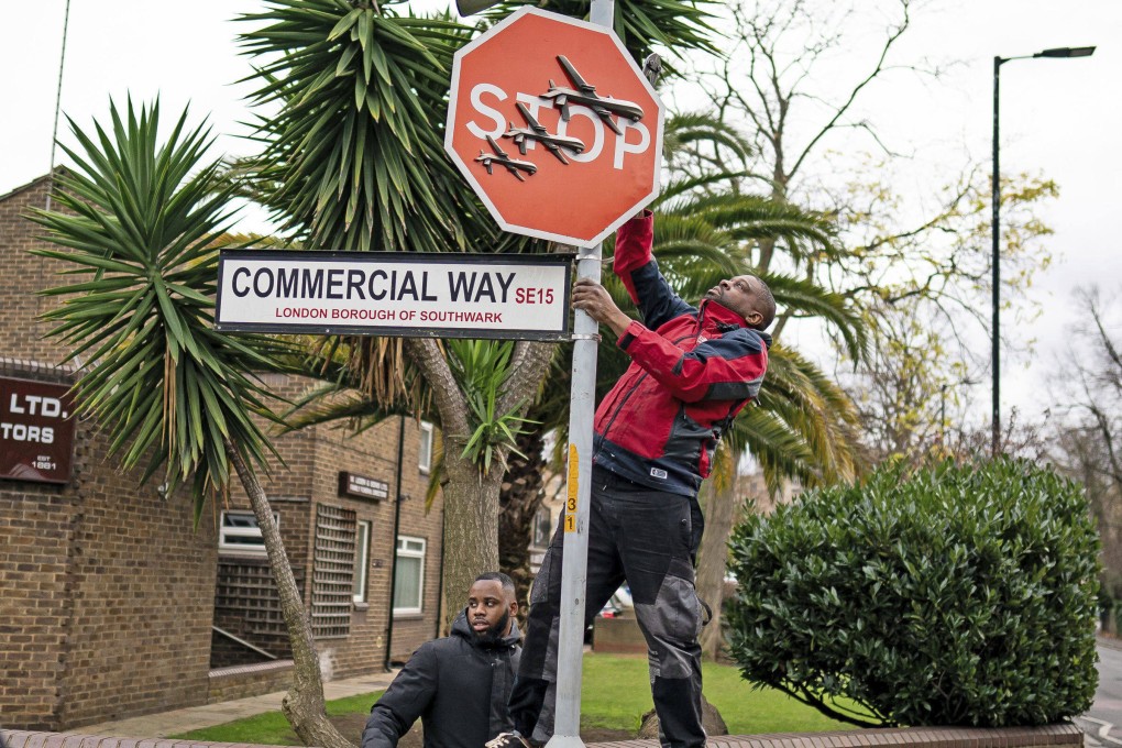 A person removes a piece of art work by Banksy in south east London on Friday. Photo: AP