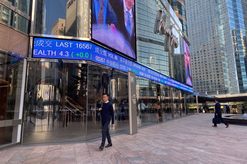 People walking outside the Exchange Square in Central, Hong Kong with tickers showing stock prices on December 7. Photo: Li Jiaxing