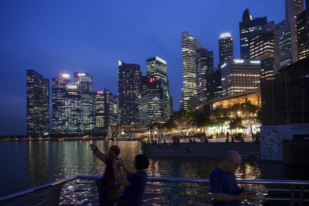 Tourists take picture with the skyline of Singapore. Andrew Lu, 58, was sentenced to 20 weeks’ jail after he pleaded guilty to five charges under the Immigration Act. Photo: AP