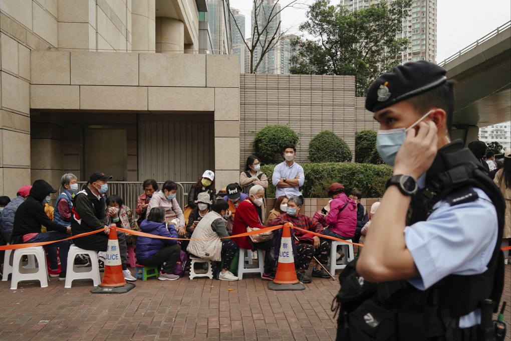 A police officer stands watch as people wait outside the West Kowloon Magistrates’ Courts ahead of the national security trial of pro-democracy activists in Hong Kong on February 6, in the biggest prosecution yet under the law introduced in 2020. Photo: AP
