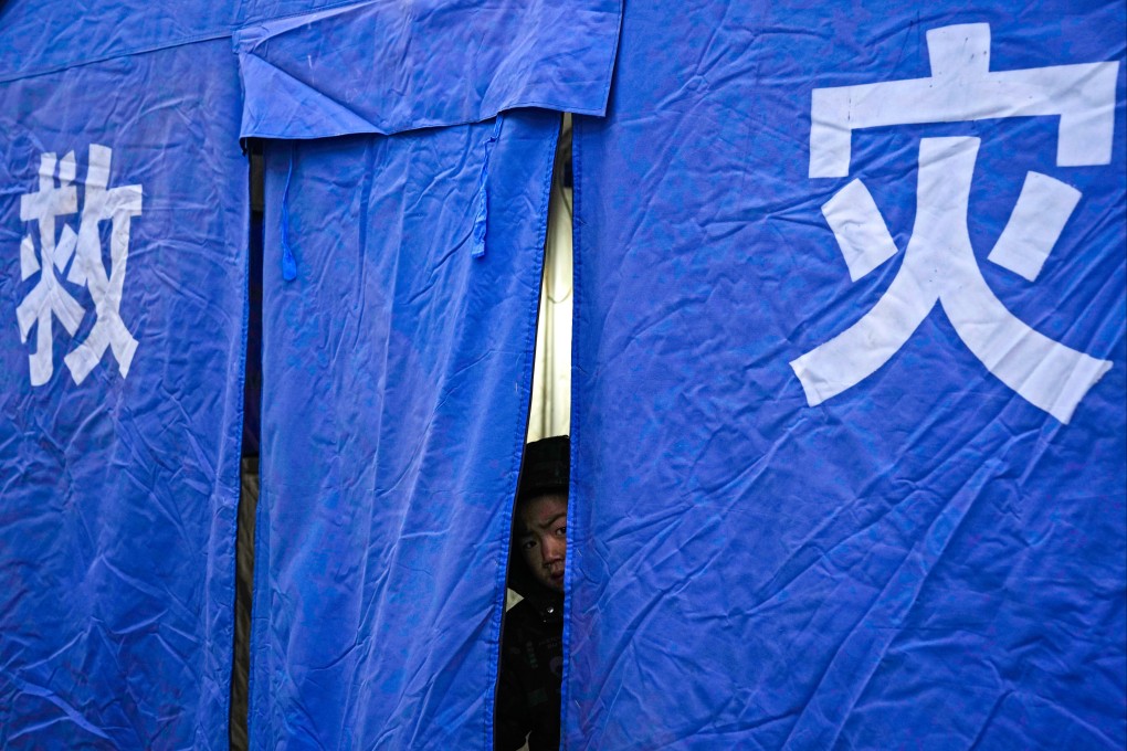 A child peeps out from a government-issued disaster relief tent after the earthquake in China’s Gansu province in December. Photo: AP