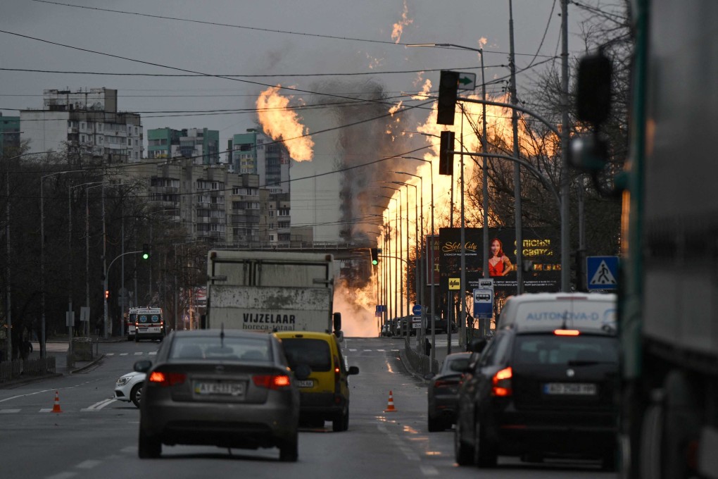 Motorists drive their cars on a road as Ukrainian firefighters attempt to extinguish a fire after a missile strike in Kyiv on Tuesday. Photo: AFP