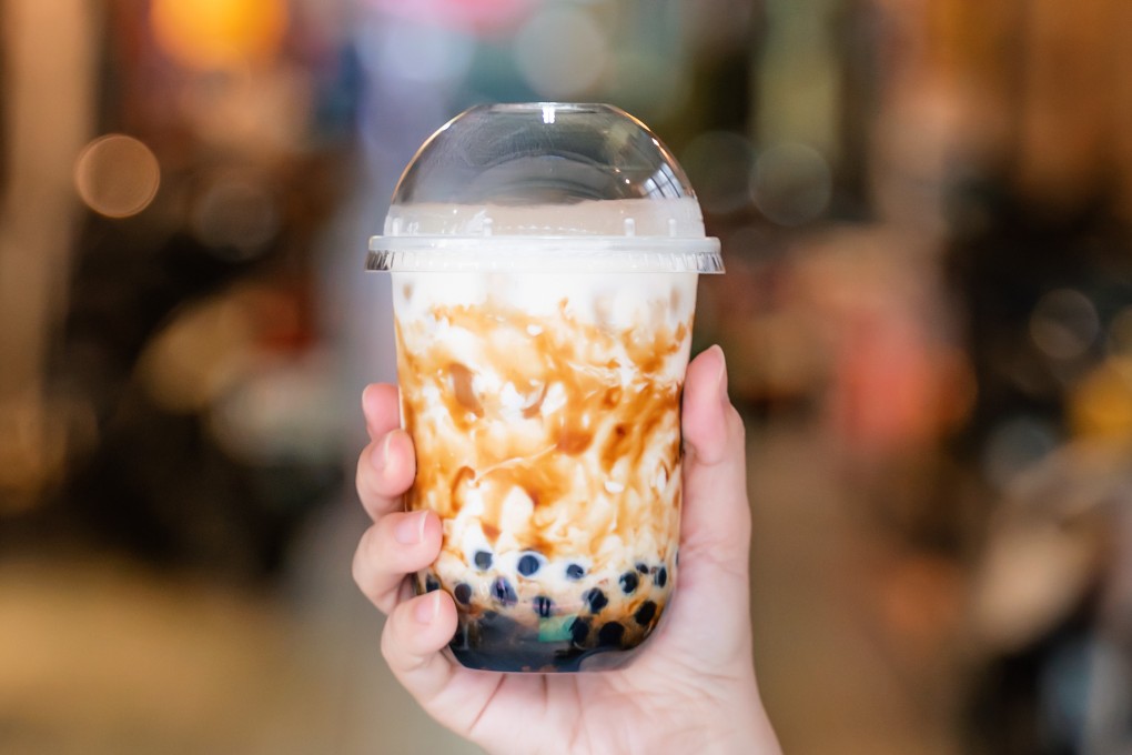 Young girl is holding and showing a cup of brown sugar flavored tapioca pearl bubble milk tea. Photo: Shutterstock