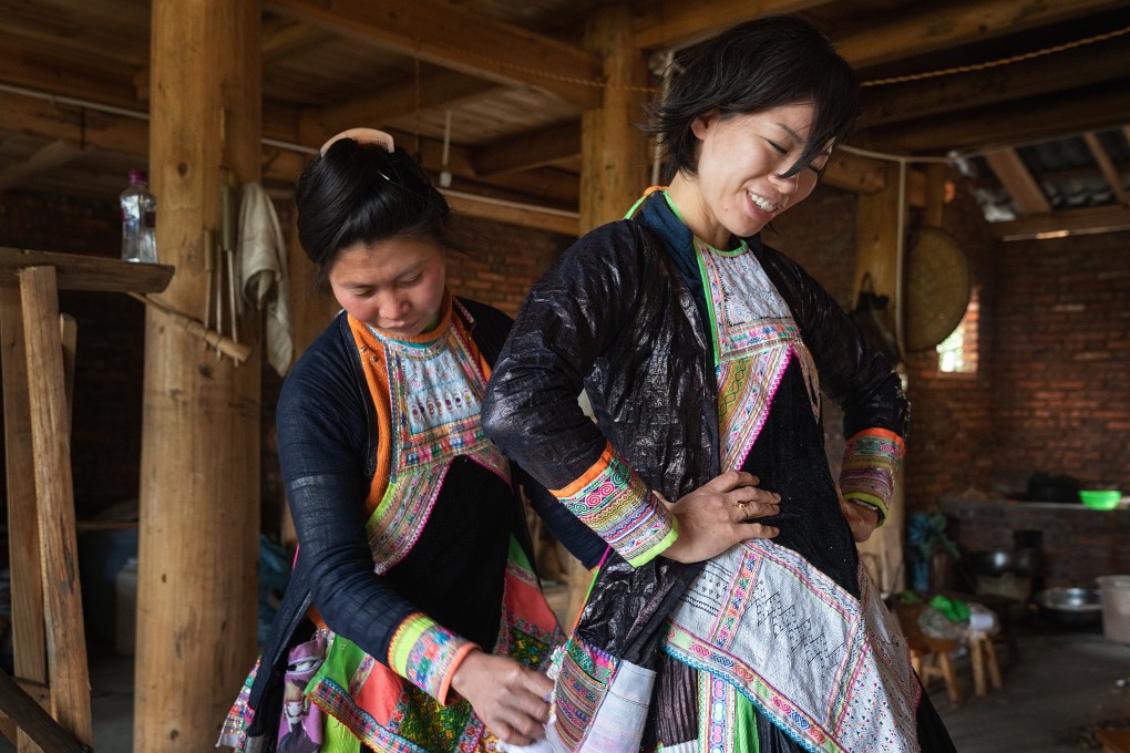 Hand-weaver Fei Fei (left) dresses American luxury fashion designer Angel Chang in one of her handmade outfits in Guizhou, China. The weaver is from the Miao ethnic minority that grows and weaves its cotton the traditional way. Photo: Justin Jin