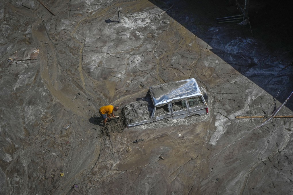 A man tries to recover a vehicle submerged in mud in  a flood-affected area along the Teesta river in Rongpo, east Sikkim, India, on October 8, 2023. Photo: AP