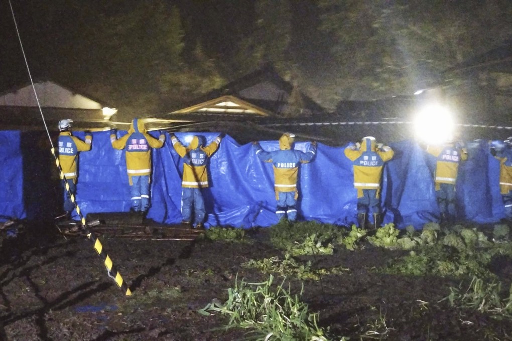 Police officers use blue sheets as a woman in 90s is rescued from a collapsed house in Suzu, Ishikawa Prefecture, in Japan on Saturday. Photo: Kyodo News via AP