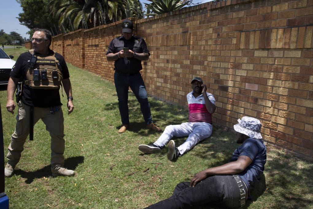 Two men, on the ground, suspected of driving a stolen vehicle, are apprehended by private security personal in Johannesburg, South Africa. Photo: AP