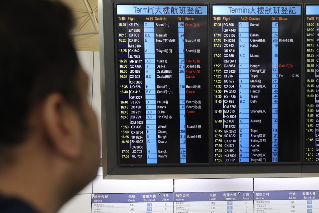 A passenger checks an information board at Hong Kong International Airport showing Cathay Pacific flight cancellations. Photo: Xiaomei Chen