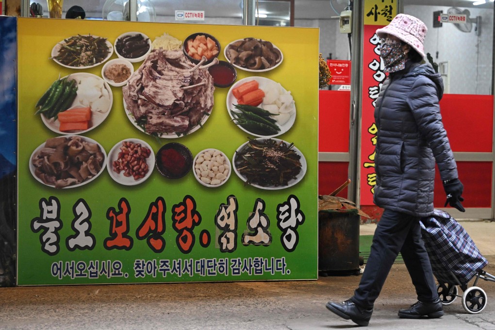 A woman walks in front of a poster showing dog meat dishes in Daegu, South Korea. On Tuesday, the country’s parliament passed a bill banning breeding, slaughtering and selling dogs for their meat, a traditional practice that activists have called an embarrassment for the country. Photo: AFP