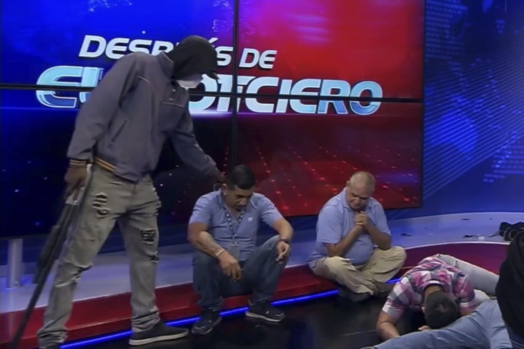 A masked gunman stands over journalists during a live television broadcast, in Guayaquil, Ecuador on Tuesday. Photo: TC Television network via AP