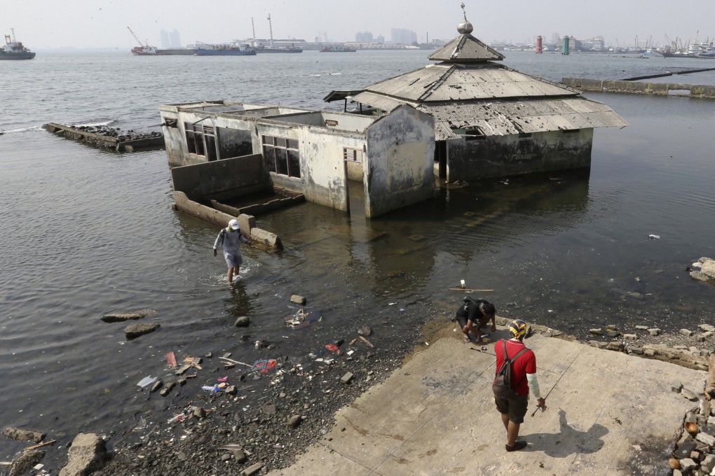 People walk near a giant sea wall which is used as a barrier to prevent sea water from flowing into land and cause flooding in Jakarta, Indonesia. Photo: AP