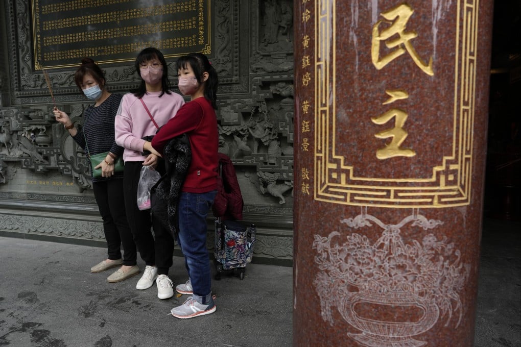 People visiting a temple stand near the words for “democracy” in Taipei on January 7. Photo: AP