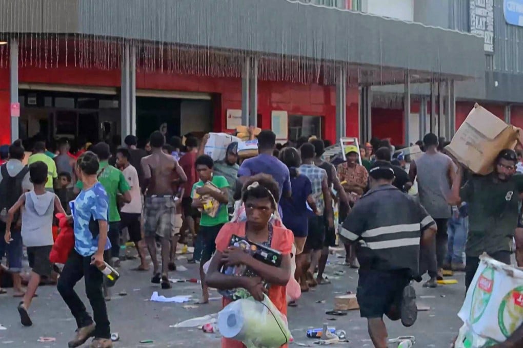Looters leave shops with goods amid a state of unrest in Port Moresby on January 10. Photo: AFP