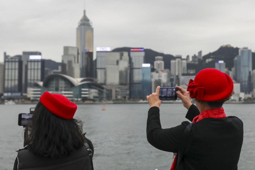People take photographs on an overcast day at the Tsim Sha Tsui waterfront on December 16. The city has been grappling with a sluggish economic recovery, weak consumption and falling stock and property markets. Photo: Xiaomei Chen