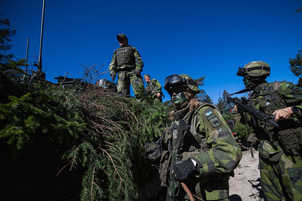 Soldiers of a regiment of the Swedish Army camouflage an armoured vehicle during an exercise on the Swedish island of Gotland on May 17, 2022. Photo: TNS