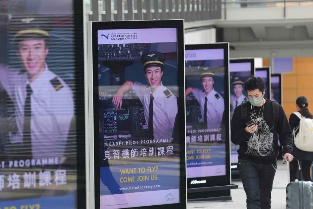 People walk past a line of Cathay recruitment advertisements at Hong Kong International Airport. The carrier pledged no new rounds of service changes beyond the Lunar New Year holiday. Photo: Xiaomei Chen