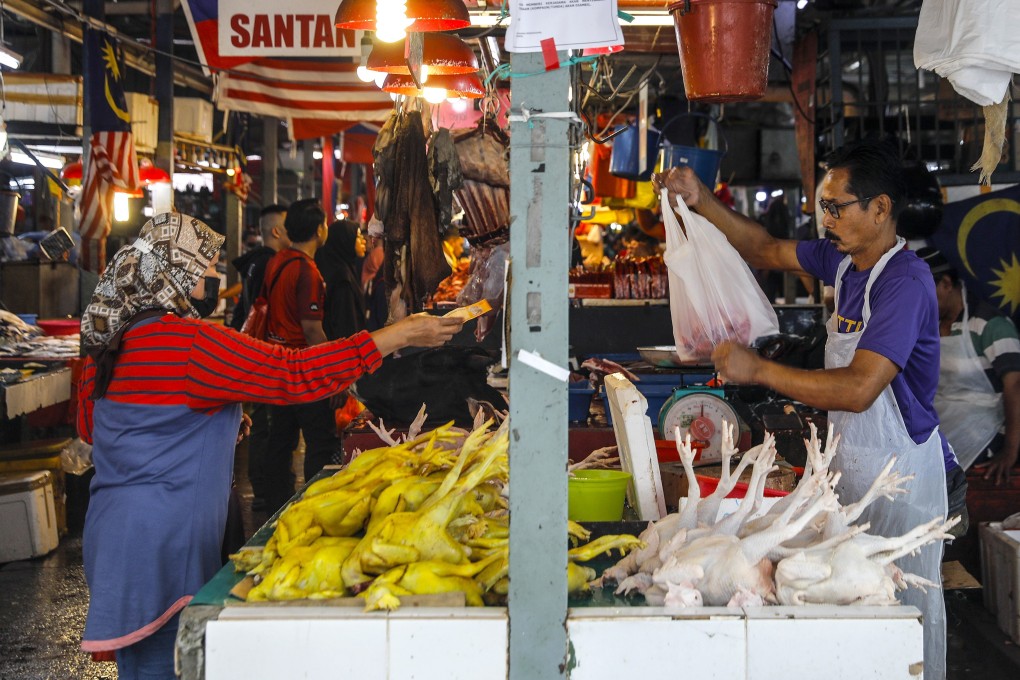 A customer buys a chicken from a vendor at a wet market in Kuala Lumpur, Malaysia. The Malaysian government said it would enact a price control scheme to ensure an ample supply of poultry. Photo: EPA-EFE