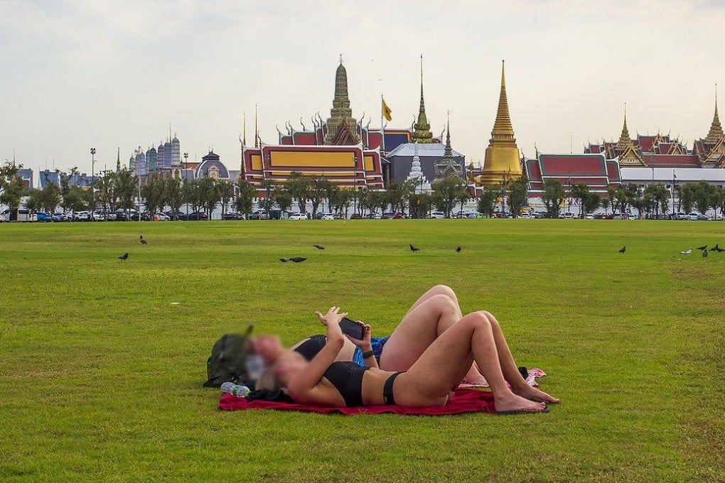 Two foreign tourists sunbathe in front of Bangkok’s Grand Palace in Thailand. Photo: Facebook/intanon.supply