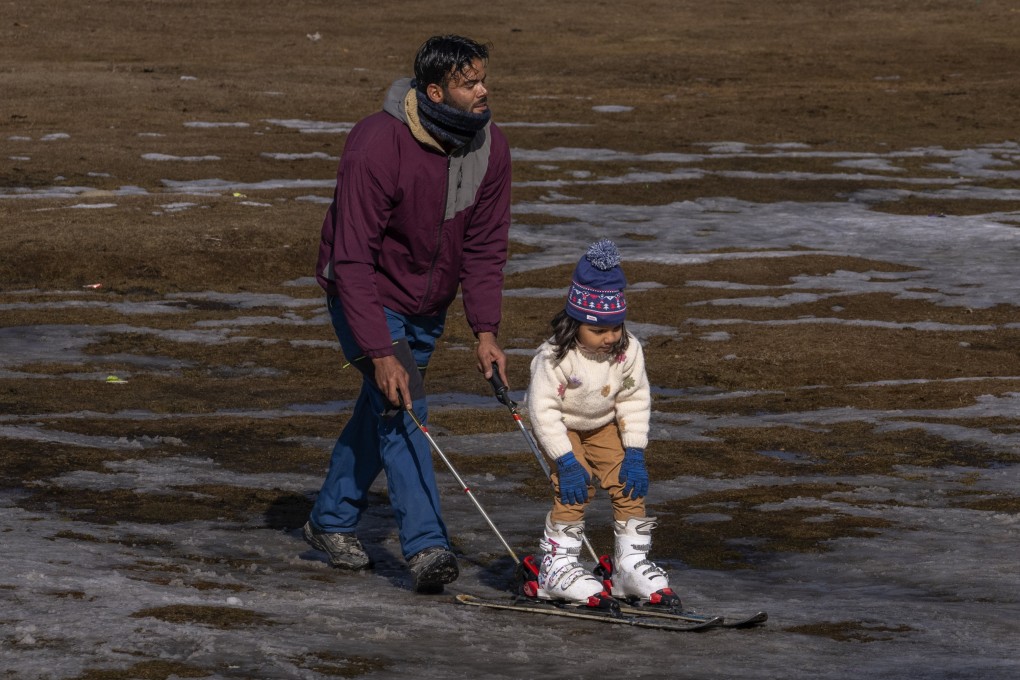 A Kashmiri ski instructor helps a young tourist to ski on a patch of snow in Gulmarg on January 13, 2024. There is hardly any snow at Gulmarg, where tourists would usually visit to ski in winter. Photo: AP