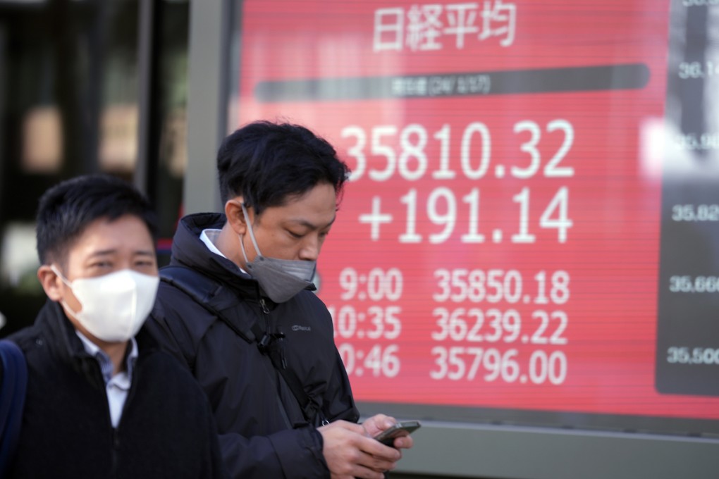 People walk in front of an electronic stock board showing Japan’s Nikkei 225 index at a securities firm in Tokyo on January 17, 2024. Photo: AP