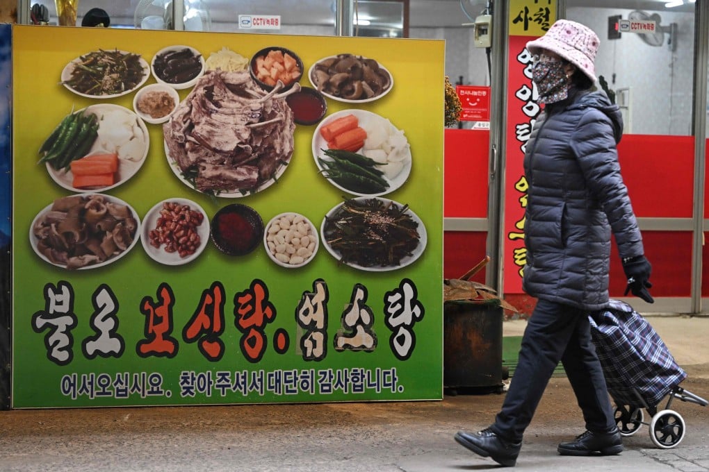 A woman walks in front of a poster advertising dog meat dishes in Daegu on January 10. Photo: AFP