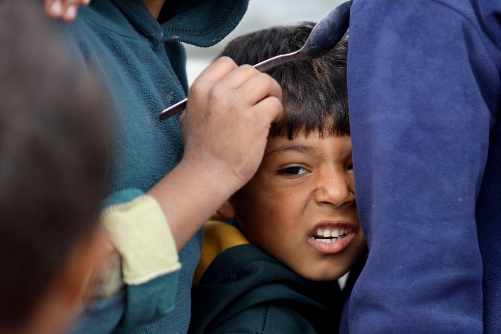 A boy in Gaza waits to receive food amid shortages of supplies. The Israel-Hamas deal includes the delivery of humanitarian aid to Gaza residents. Photo: Reuters